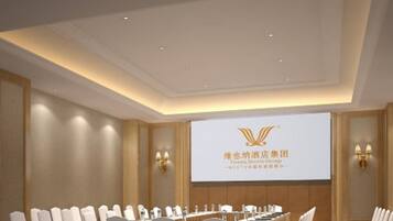 A conference room with a long table, white chairs, and a projection screen displaying hotel group information.