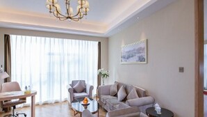 Quarto de hotel moderno com lustre, sofá, mesa de centro e escrivaninha.