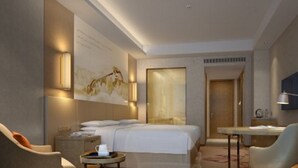Quarto de hotel moderno com cama, escrivaninha, cadeira e mesa pequena.