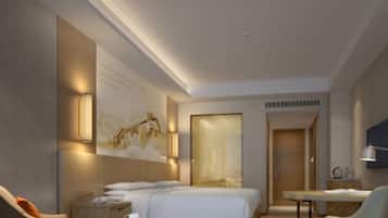 A modern hotel room with a bed, a desk, a chair, and a small table.