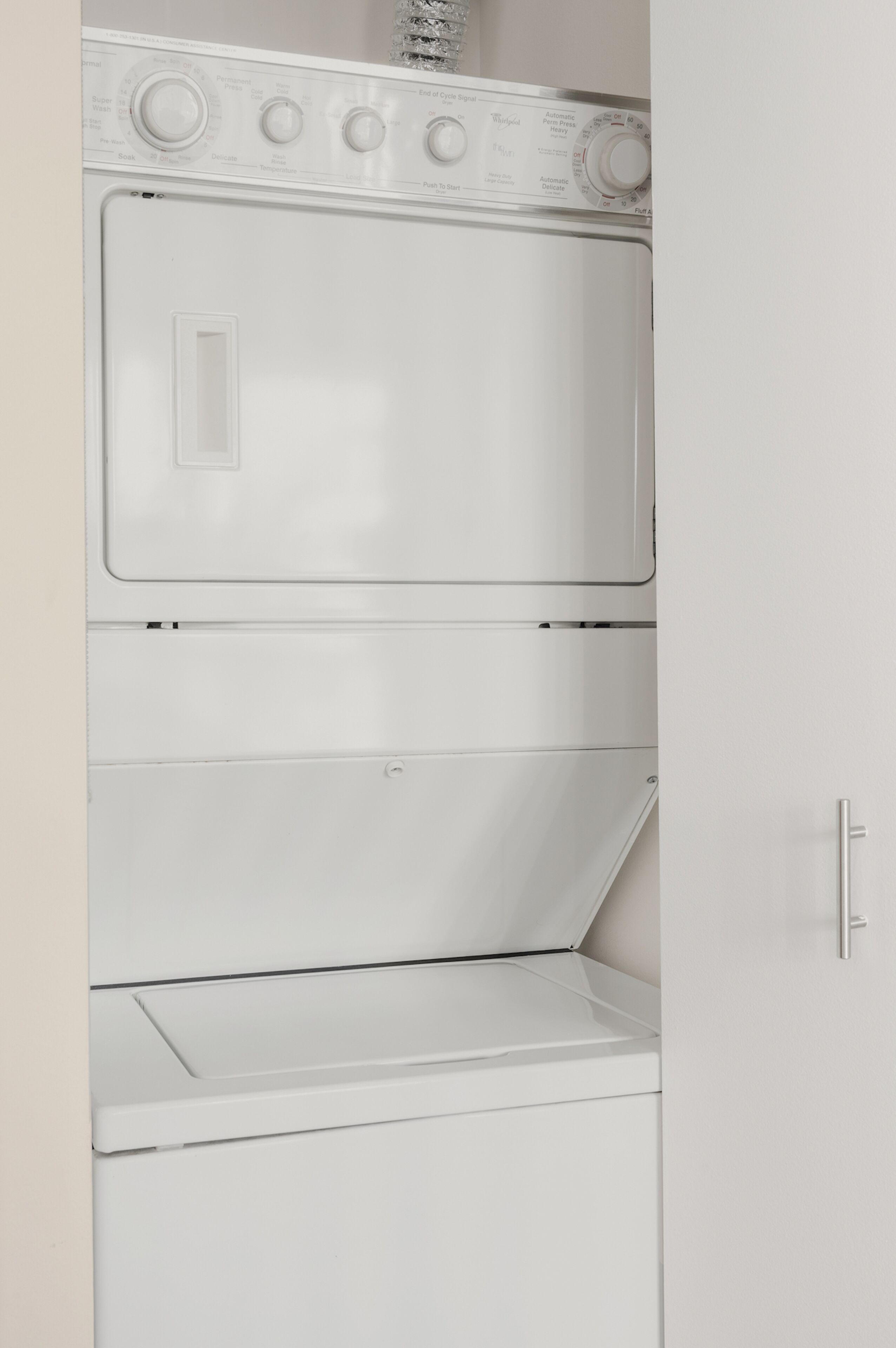 A white wall-mounted washer and dryer unit with control knobs and a door.