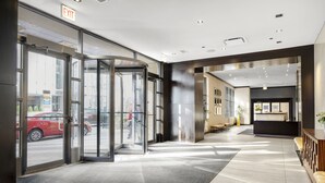 Un vestíbulo de hotel con una puerta giratoria, una recepción y un área de espera con asientos.
