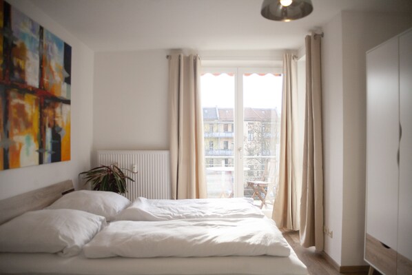 Un dormitorio con cama, radiador, ventana con cortinas y una planta.
