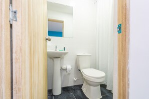A small bathroom with a white sink, toilet, and mirror. - Ayenda Malaki (Medellín)