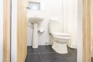 A bathroom with a white sink, toilet, and dark tiled floor.
