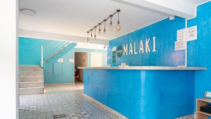 A reception area with a blue wall and a tiled floor, a staircase, and a counter with the name 'MALAKI'. - Ayenda Malaki (Medellín)