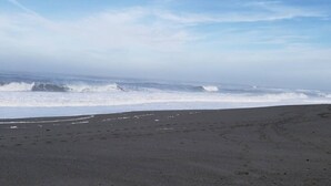 Ein Strand mit Wellen, blauem Himmel und sandigem Ufer.