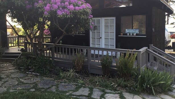 Ein Haus mit Veranda, Treppe und einem Schild, auf dem 'BEJA BLUE COTTAGE' steht.