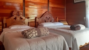 A wooden-paneled room with two beds, each with a unique headboard design. - Cabaña Luna Roja (Ocosingo)