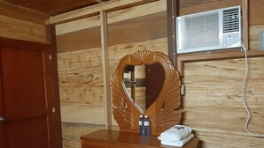 A wooden cabin room with a wooden dresser, a large mirror, and a wall-mounted air conditioner. - Cabaña Luna Roja (Ocosingo)