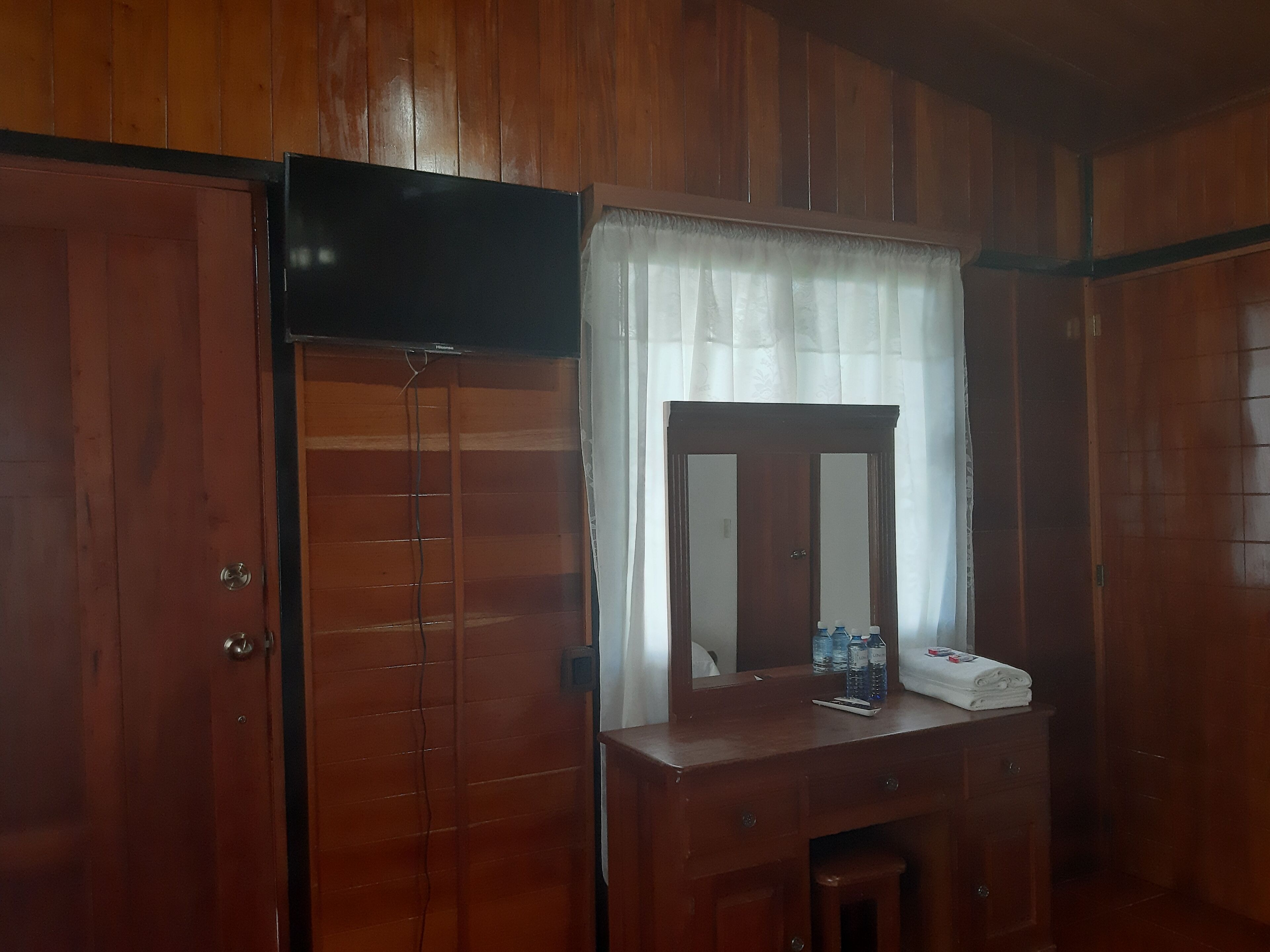 A wooden room with a wardrobe, a mirror, and a television mounted on the wall.