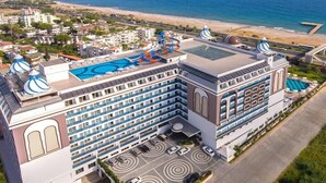 Um hotel com piscina no terraço, várias varandas e vista para a praia.