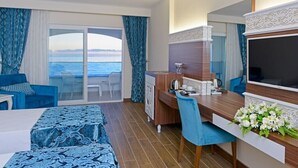 Quarto de hotel com varanda, área de refeições, televisão e cama.