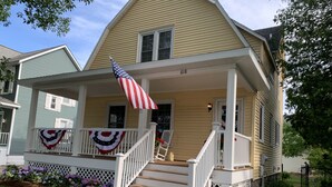 Une maison à deux étages avec un porche, un drapeau et le numéro 618 sur la façade.