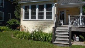 Une maison à deux étages avec un porche à l’avant et un petit jardin.