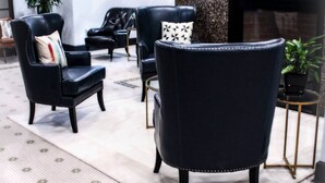 A modern lobby with black leather armchairs, a patterned rug, and a fireplace.
