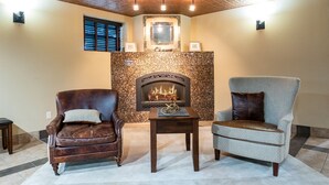 A cozy room with a fireplace, two armchairs, and a small table.