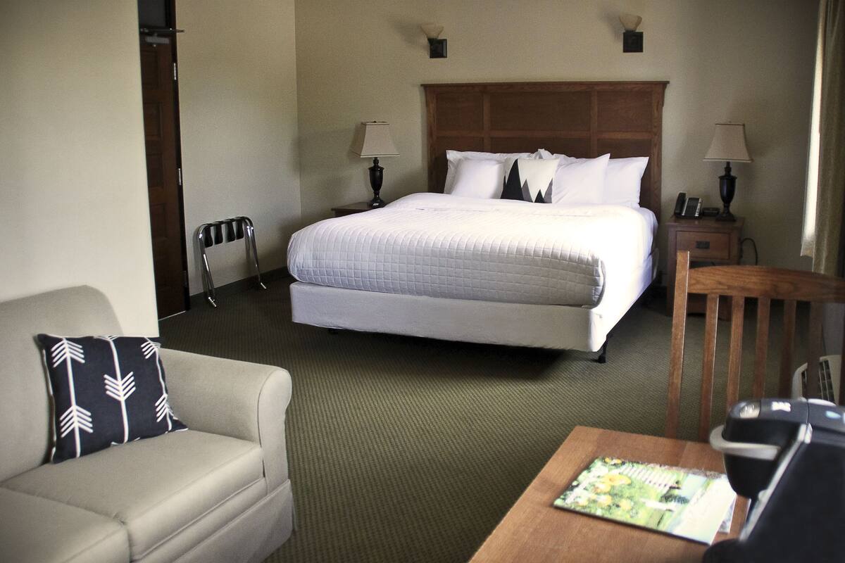 A hotel room with a bed, a sofa, a table, and two chairs.
