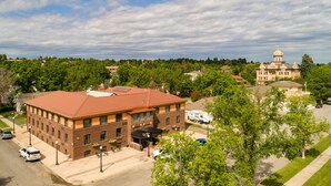 A large brick building with a red roof, a covered outdoor seating area, and a flagpole.