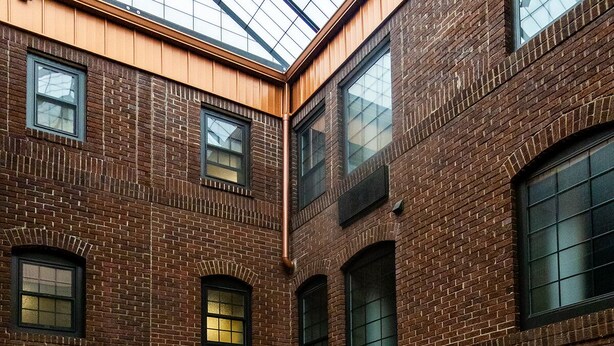 A spacious atrium with high ceilings, large windows, and a central seating area with tables and chairs.