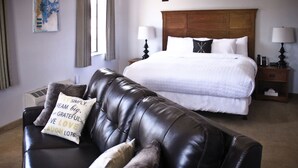 A hotel room with a large bed, a leather sofa, and a wall-mounted artwork.