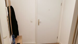 A room with a wooden floor, a white door, and a small wooden cabinet with a water bottle on it. - Nice Flat near Town Center & Wöhrder See (Nuremberg)