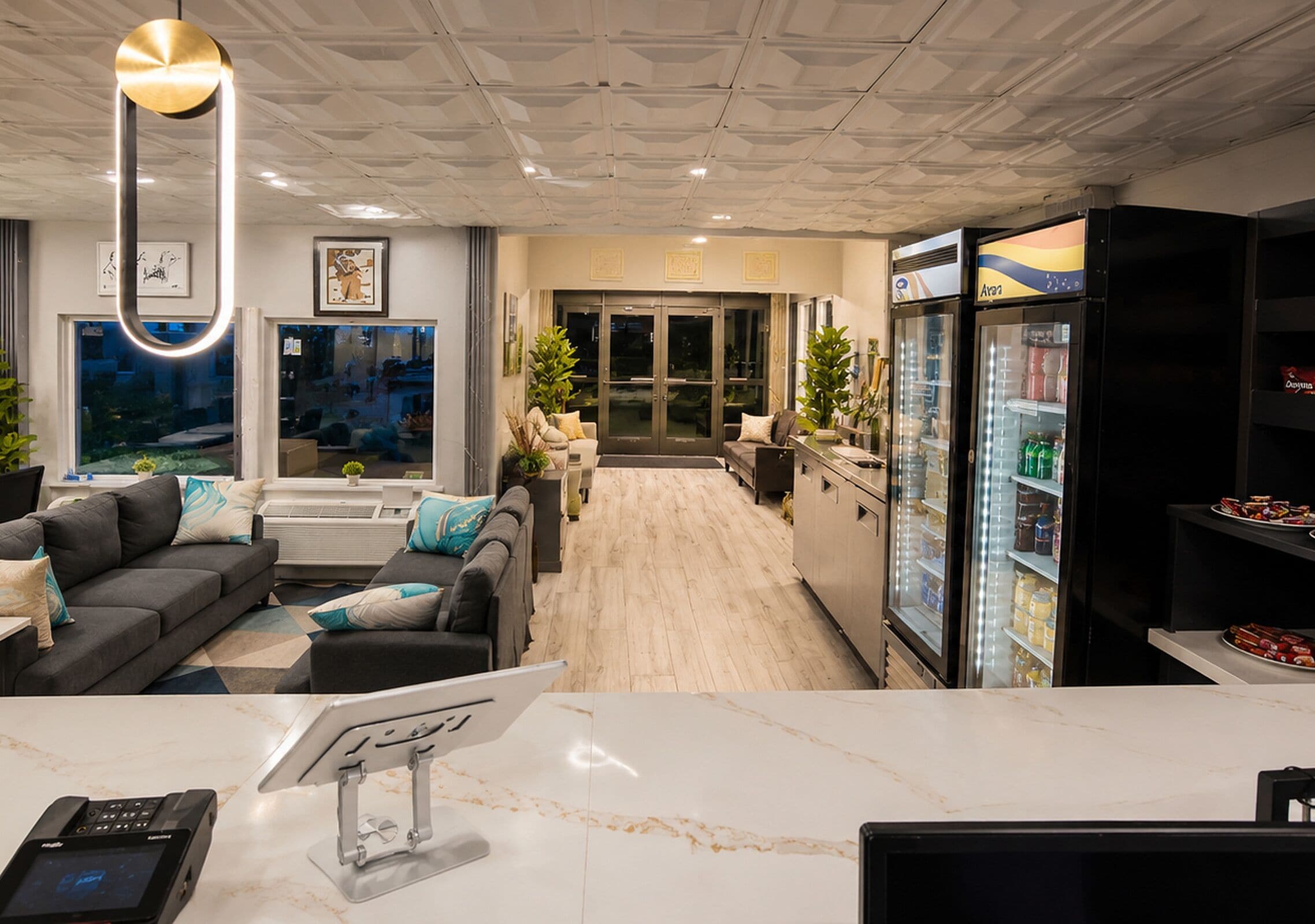 A hotel lobby with a reception desk, seating area, and a refrigerator stocked with beverages.
