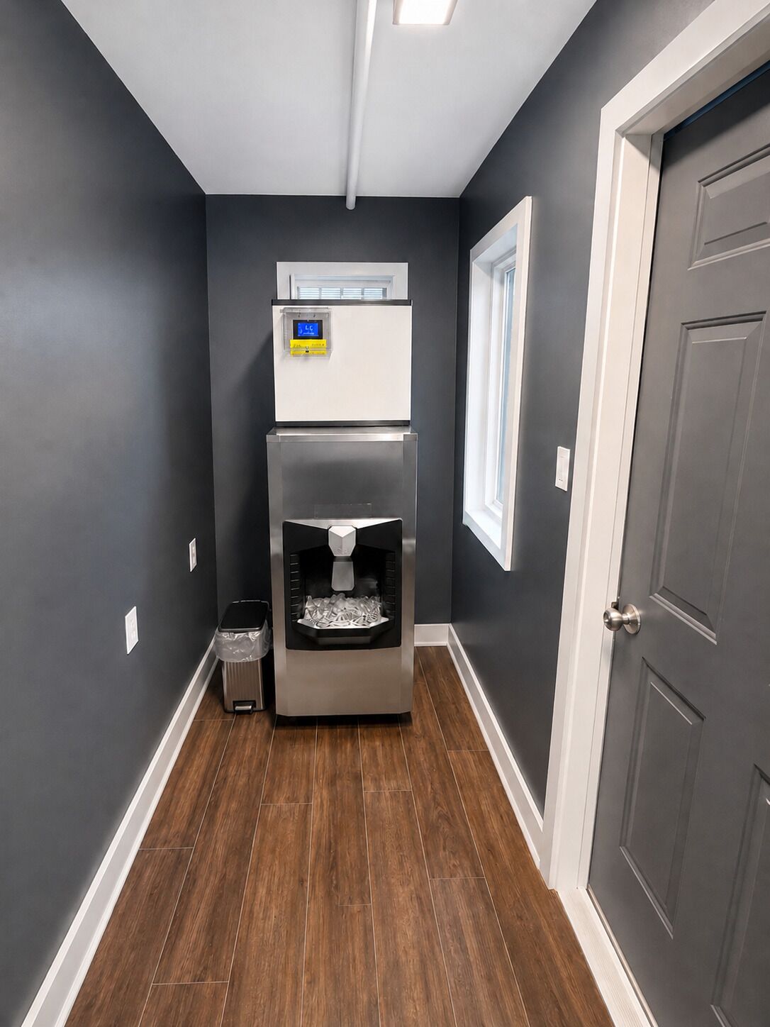 A hallway with a water dispenser, a trash can, and a door.
