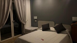 A hotel room with a bed, two bedside tables, a nightstand, and a sliding glass door with curtains. - B&B Bethel Napoli (Naples)