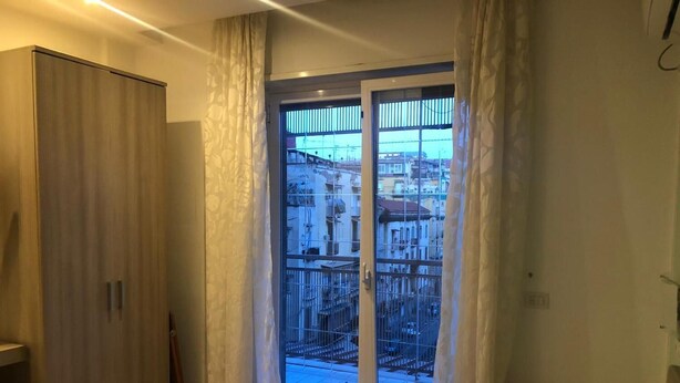 A bedroom with a large sliding glass door leading to a balcony with a city view. - B&B Bethel Napoli (Naples)