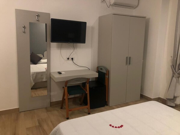 A bedroom with a bed, a desk, a chair, a wardrobe, and a TV mounted on the wall. - B&B Bethel Napoli (Naples)