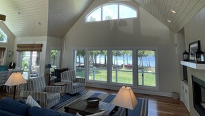 Ein geräumiges Wohnzimmer mit hoher Decke, großen Fenstern und einem Kamin.