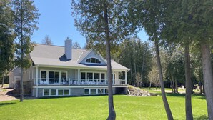 Ein großes, zweistöckiges Haus mit überdachter Veranda und gepflegtem Rasen.