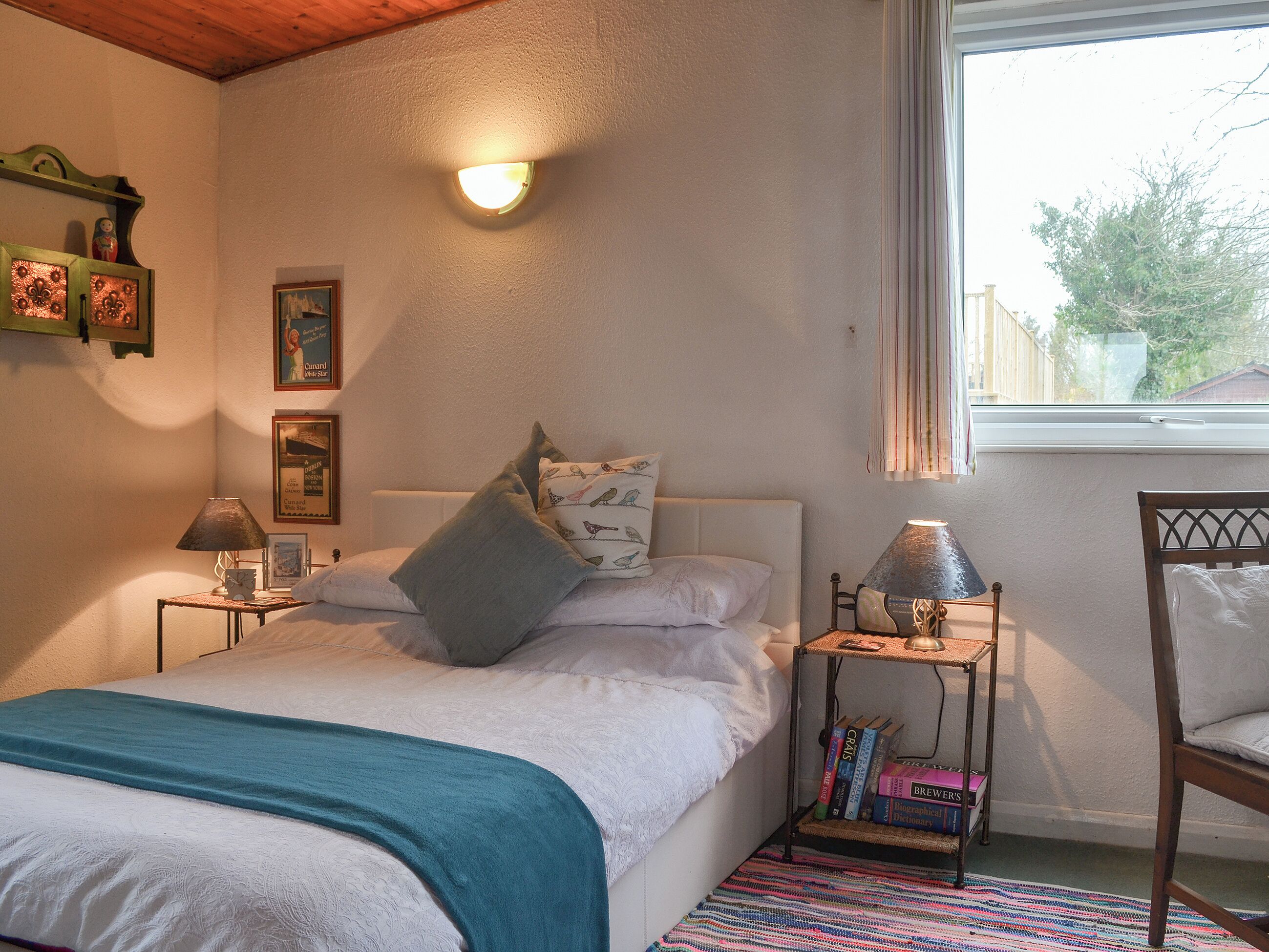 A bedroom with a bed, bedside tables, a window, and a bookshelf.