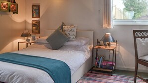 Une chambre à coucher avec un lit, des tables de chevet, une fenêtre et une bibliothèque.