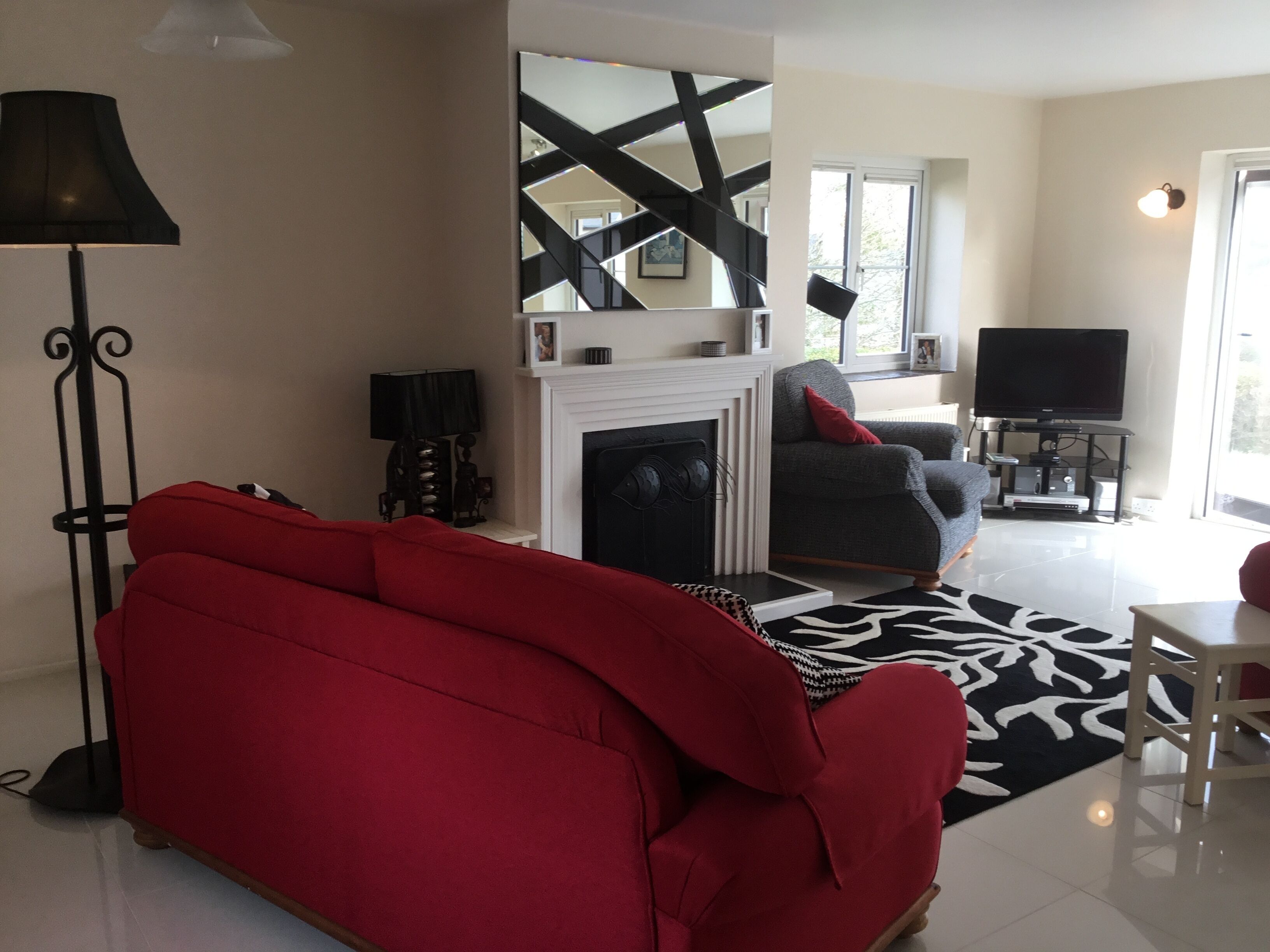A living room with a red sofa, a fireplace, a television, and a modern staircase.