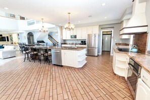 A spacious kitchen with a large island, stainless steel appliances, and a herringbone-patterned floor. - OCEANFRONT, 17 BRs, Ocean Views, Priv Pool, Rec Rm, Theatr Rm! 4x1487, The Dream (Corolla)