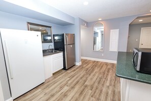 A kitchen with white cabinets, a stainless steel refrigerator, a microwave, and a sink. - OCEANFRONT, 17 BRs, Ocean Views, Priv Pool, Rec Rm, Theatr Rm! 4x1487, The Dream (Corolla)