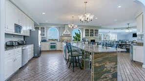 A spacious kitchen with white cabinetry, a large island, and a dining area with multiple chairs.