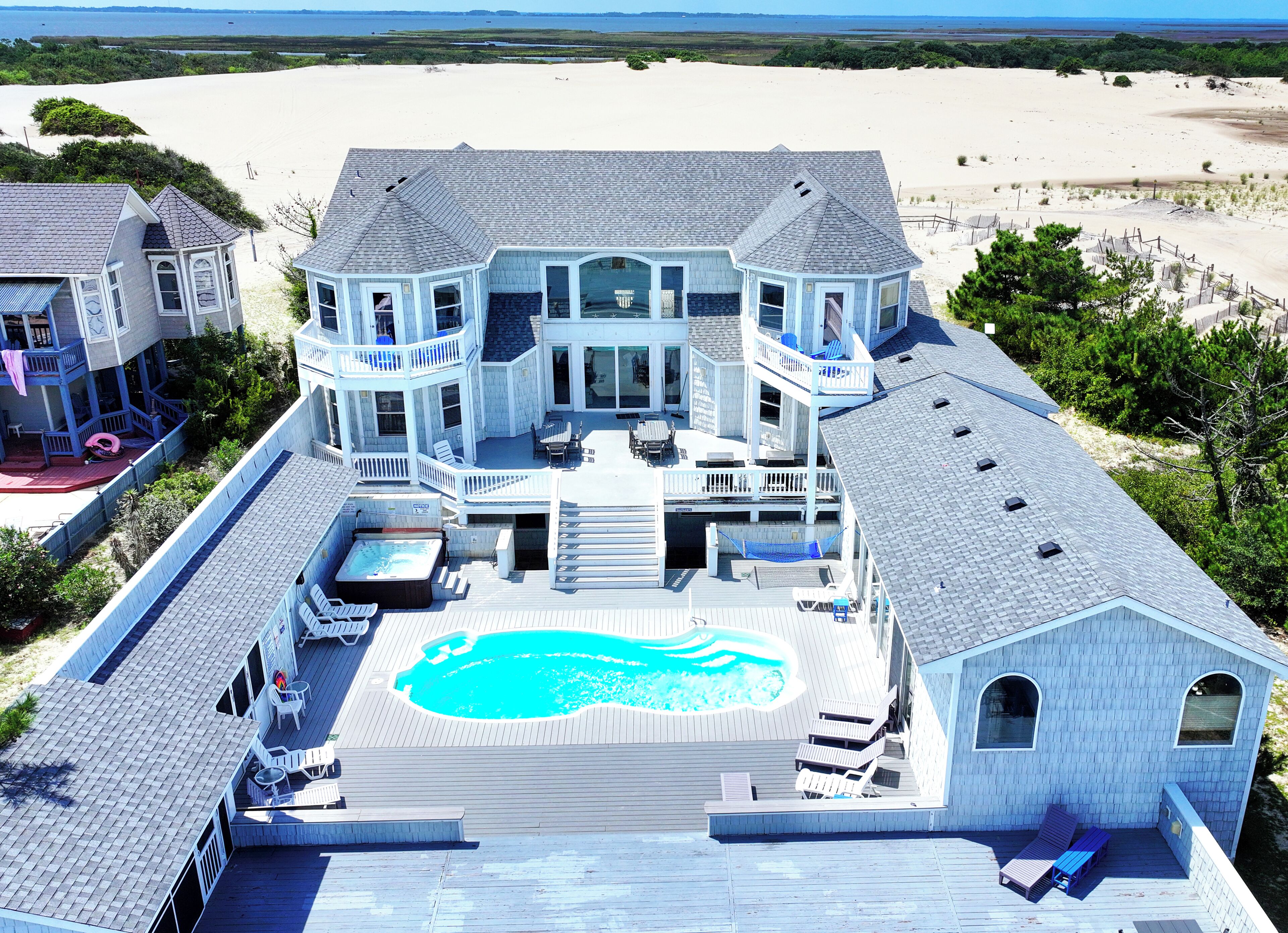 Ein großes Haus mit Swimmingpool, mehreren Terrassen und Blick auf den Strand.