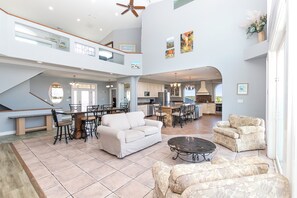 A spacious living area with a high ceiling, a dining table with chairs, a sofa, and a coffee table. - OCEANFRONT, 17 BRs, Ocean Views, Priv Pool, Rec Rm, Theatr Rm! 4x1487, The Dream (Corolla)