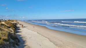 A beach with a wooden boardwalk leading to a sandy shore.