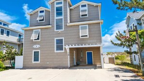 A two-story residential building with a covered front porch, a blue door, and a visible number "709". - OCEANFRONT, Ocean Views, Private Pool, Pool Table, Dogs Welcome, OS7Q, Dune Nothin (Corolla)