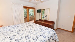 A bedroom with a large bed, a wooden dresser, a ceiling fan, a TV, and a sliding glass door to a balcony. - Oceanside, Private Pool, Golf Cart, Bar, Hot Tub, Rec Rm, SS4, Sunning Your Bunns (Southern Shores)