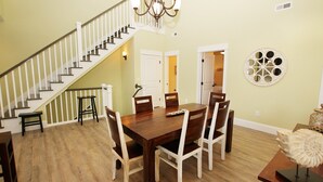 A dining area with a wooden table and chairs, a staircase with white railings, and a chandelier. - Oceanside, Patio, Hot Tub, Rec Room, BV8A, Break Away (Corolla)
