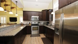A modern kitchen with dark wooden cabinets, stainless steel appliances, granite countertops, and pendant lighting. - Oceanside, Patio, Hot Tub, Rec Room, BV8A, Break Away (Corolla)