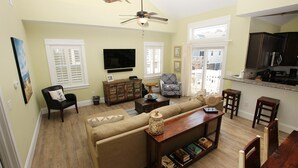 A living room with a sofa, armchairs, a coffee table, a TV, and a kitchen area with cabinets and a microwave. - Oceanside, Patio, Hot Tub, Rec Room, BV8A, Break Away (Corolla)