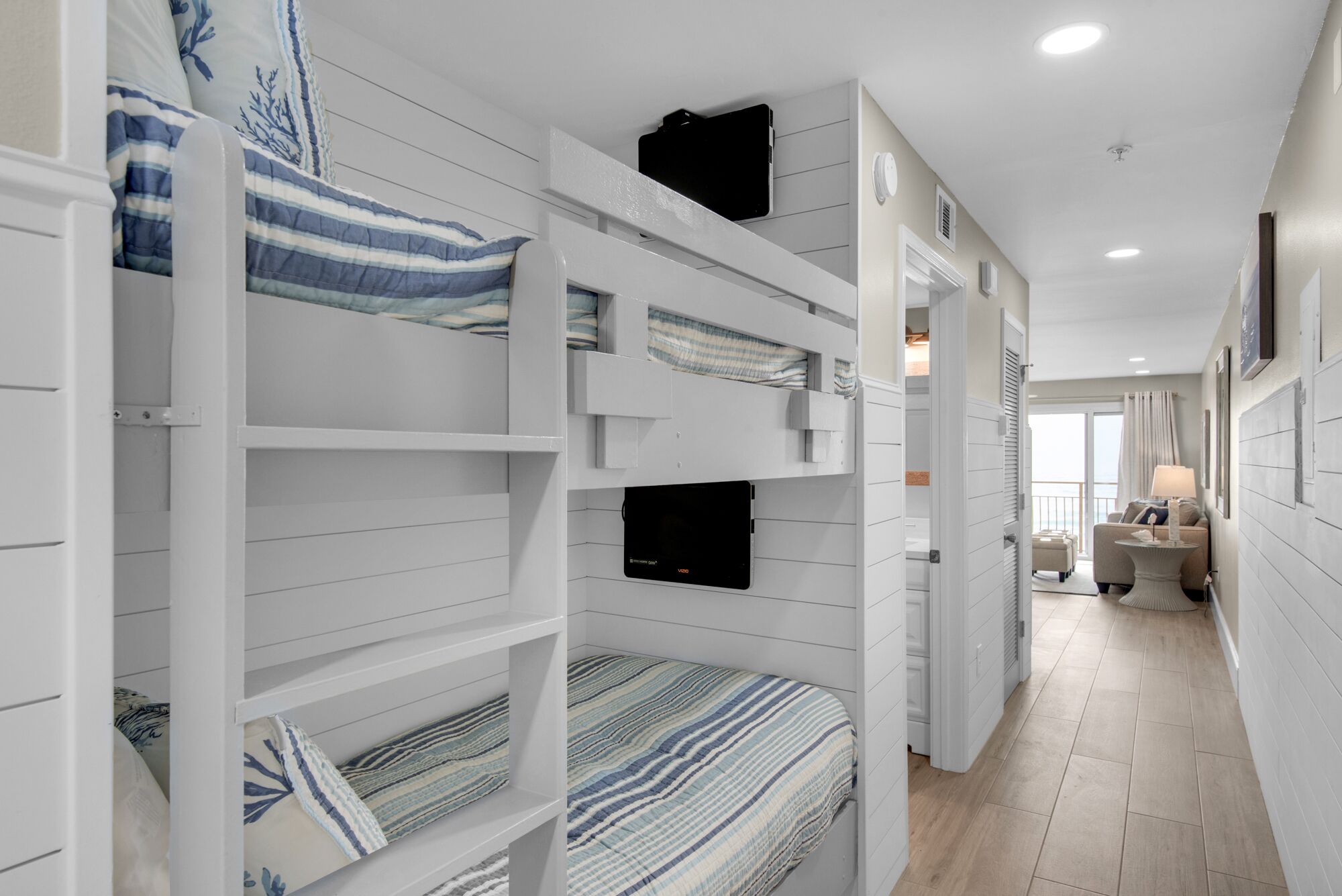 Een hotelkamer met stapelbedden, een nachtkastje, een lamp en uitzicht op het balkon.