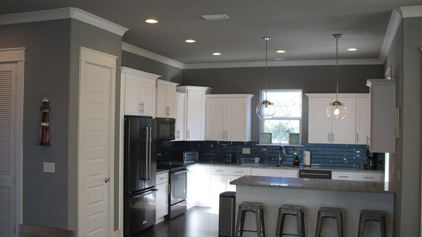 A modern kitchen with white cabinets, stainless steel appliances, and a central island with bar stools.