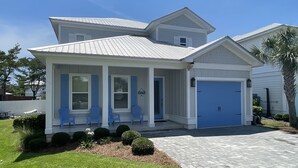 A two-story house with a covered porch, a blue garage door, and a well-maintained lawn.